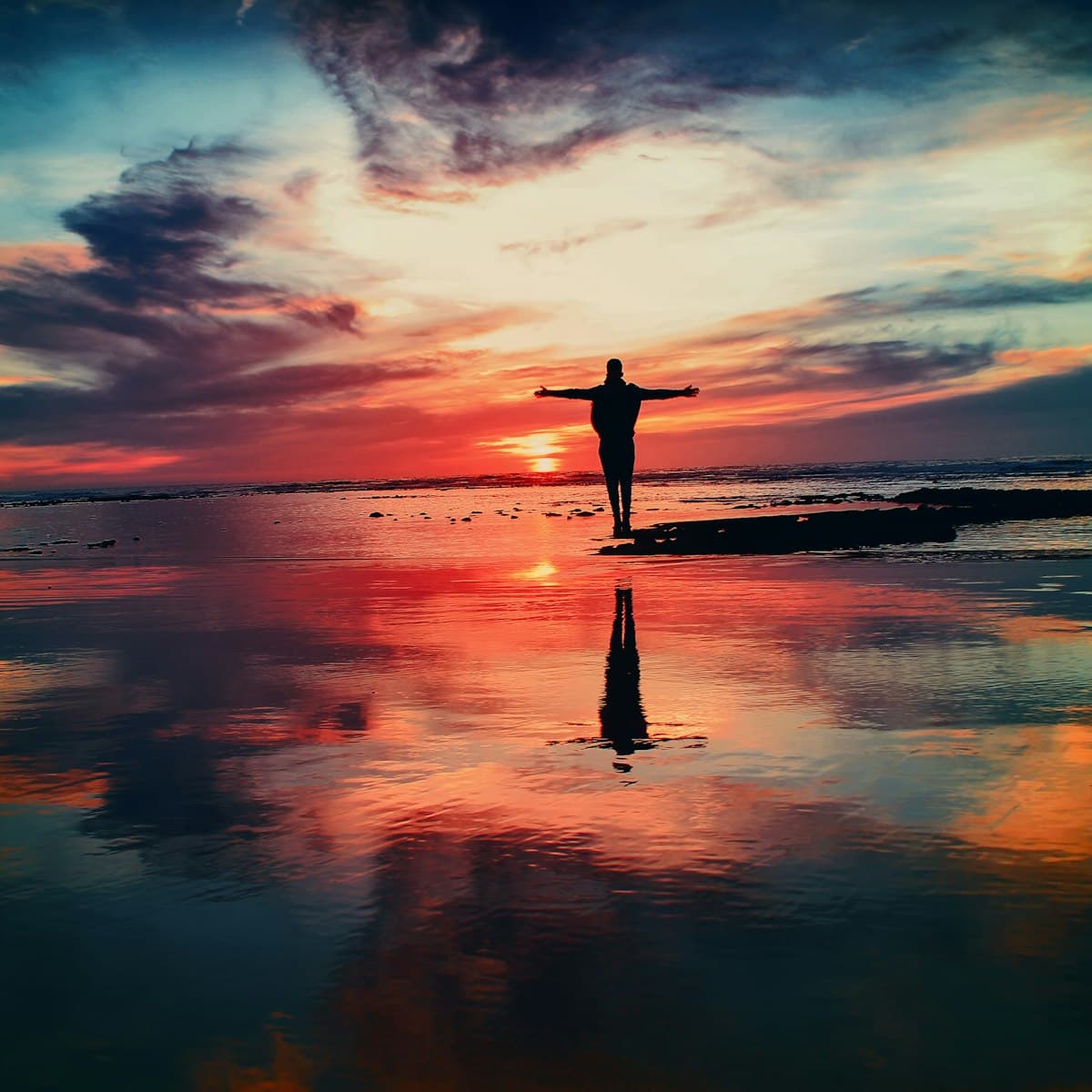 Silhouette of a person on a rock surrounded by calm water
